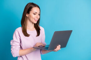 パソコンを手に持って立っている長髪の女性