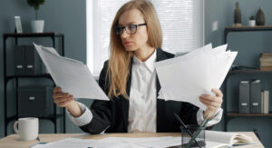 Businesswoman holding heaps of papers